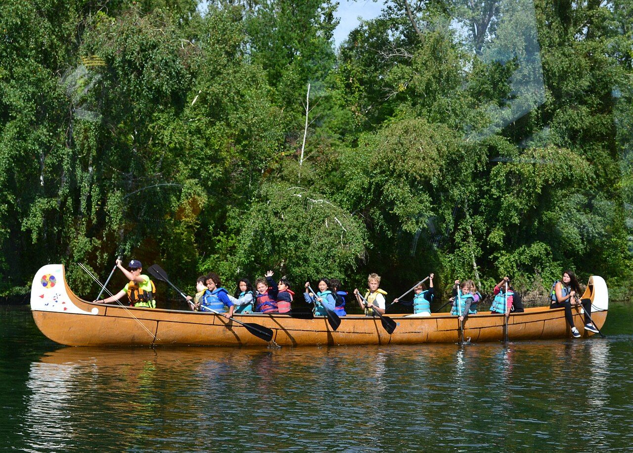 Students paddling a large canoe together in Canada